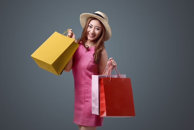 Young asian woman with hat and colored shopping bags 