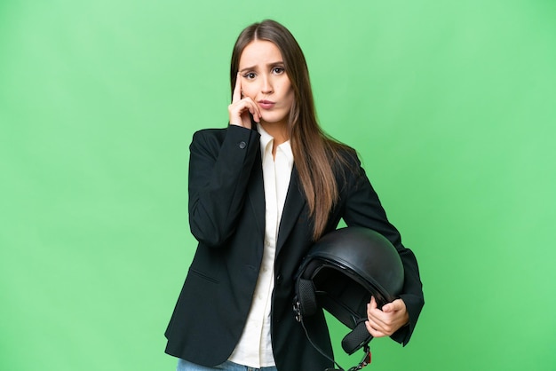 Young Asian woman with a motorcycle helmet over isolated chroma key background thinking an idea