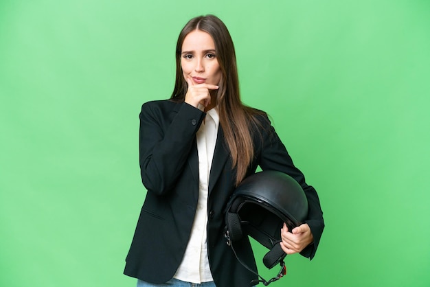 Giovane donna asiatica con un casco da motociclista sopra il pensiero di fondo chiave cromatica isolato