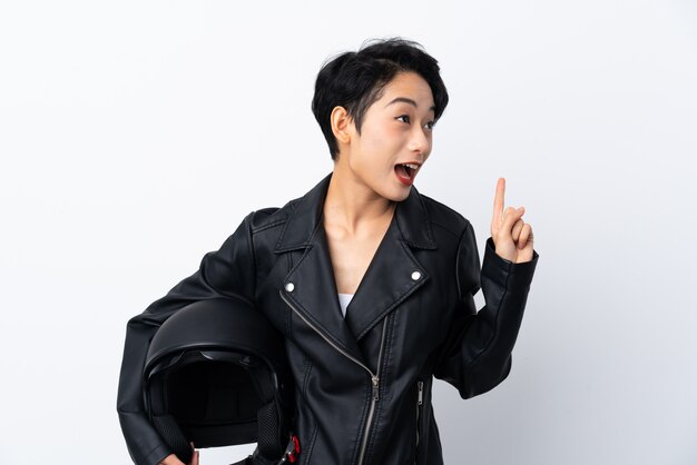 Young Asian woman with a motorcycle helmet over isolated white wall intending to realizes the solution while lifting a finger up