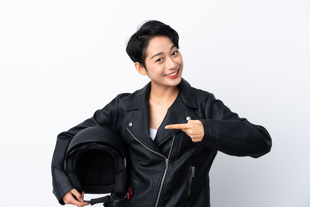 Young Asian woman with a motorcycle helmet over isolated white wall and pointing it