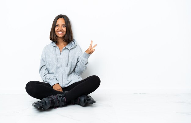 Young asian woman with roller skates on the floor smiling and showing victory sign