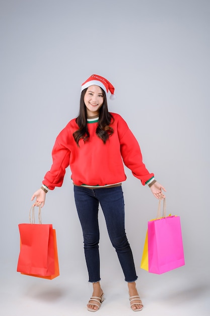 쇼핑백과 산타 모자와 젊은 아시아 여성