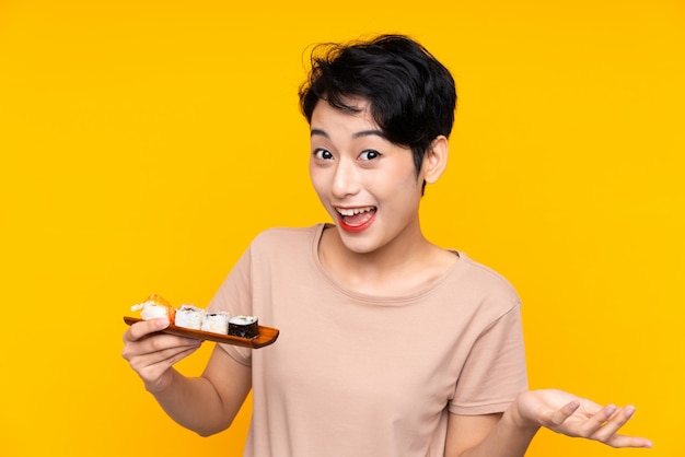 Giovane donna asiatica con sushi con espressione facciale scioccata