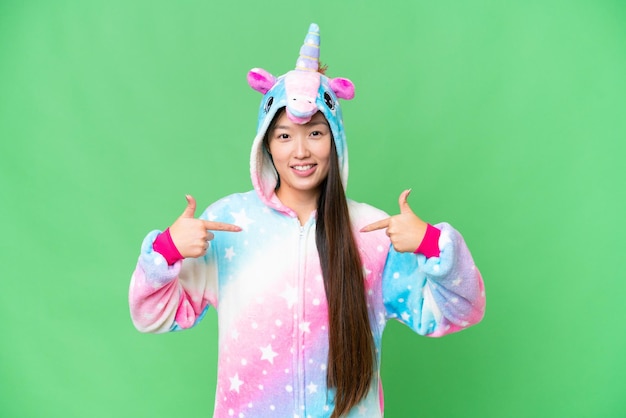 Молодая азиатка в пижаме единорога на изолированном фоне хроматического ключа гордая и самодовольная