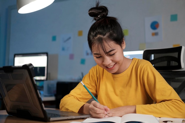 Young Asian woman working and learning at night at home office.