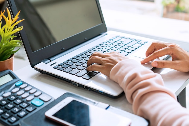 Young Asian woman working online with computer laptop at home while sitting on the sofa. Close up.