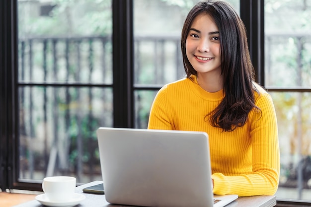 Young Asian woman working with laptop for online shopping in coffee shop or coworking space