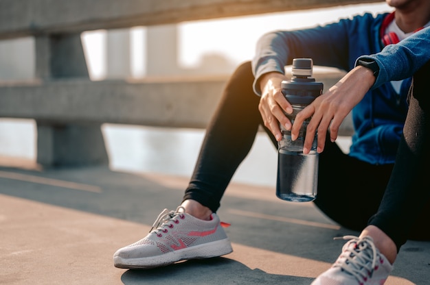 Le giovani donne asiatiche bevono acqua e si siedono per riposare dopo aver fatto jogging un allenamento mattutino in città