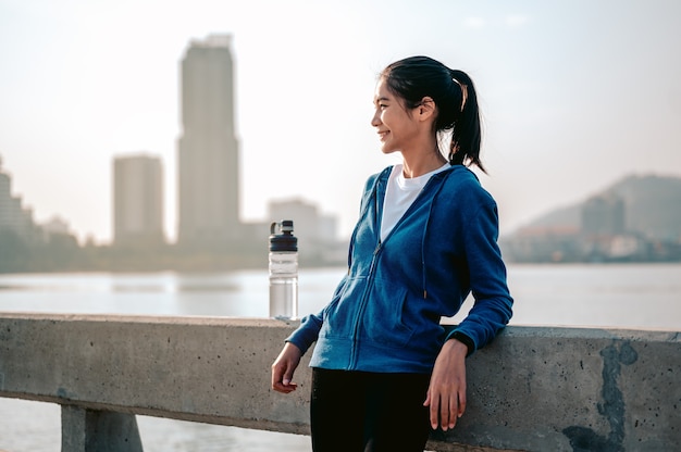 Young asian women stand to rest after jogging a morning workout in the city A city that lives