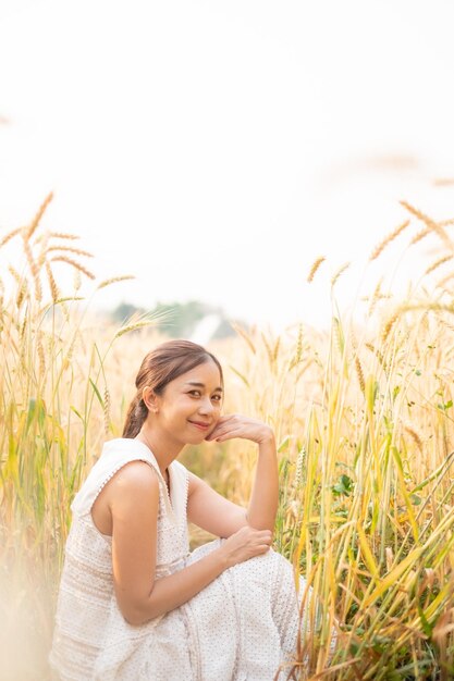 Young Asian women in white dresses sitting in the Barley rice field