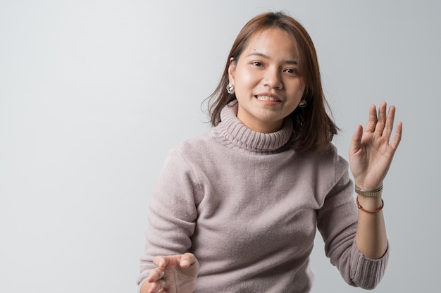 長いシャツと白い背景の上のスタジオファッションのコンセプトでジーンズの若いアジア女性