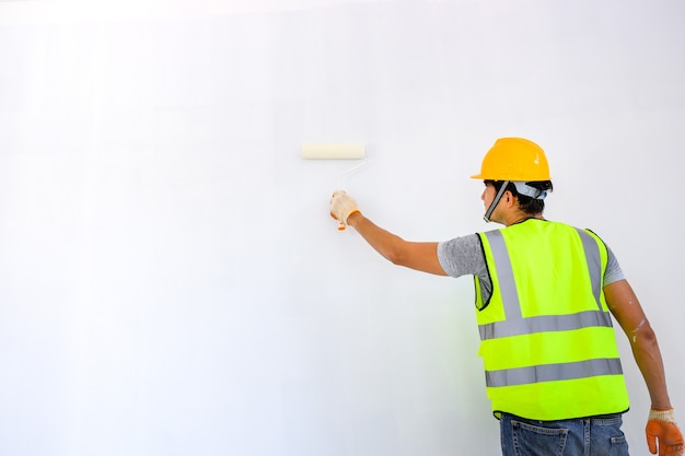 young asian worker As a painter to paint the walls in the house and use a roller to paint the white primer on the construction site