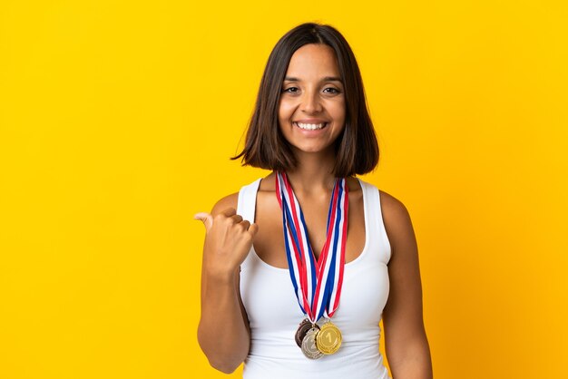 Young asiatic woman with medals isolated on white background pointing to the side to present a product