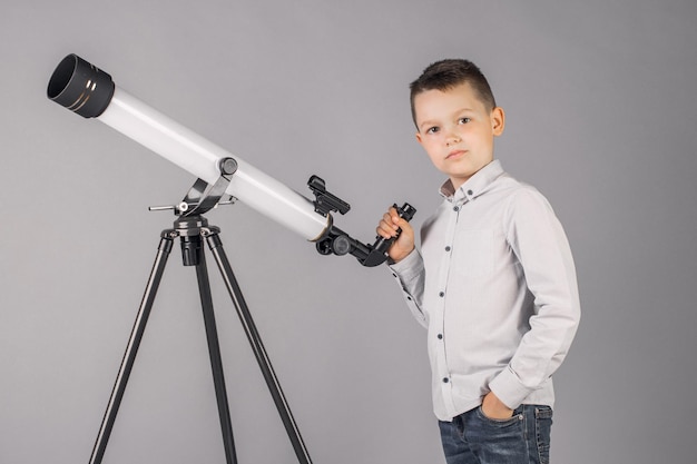 Young astronomer looks through a telescope and writes in the tablet