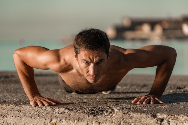 Foto giovane atleta facendo flessioni in riva al mare