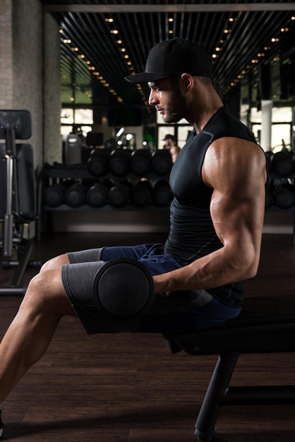 Young Athlete In The Gym Performing Biceps Curls With A Dumbbells