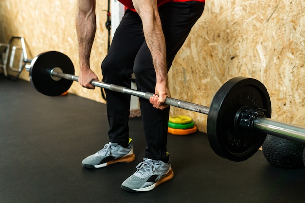 Young athlete lifting barbell with dumbbells exercising in gym