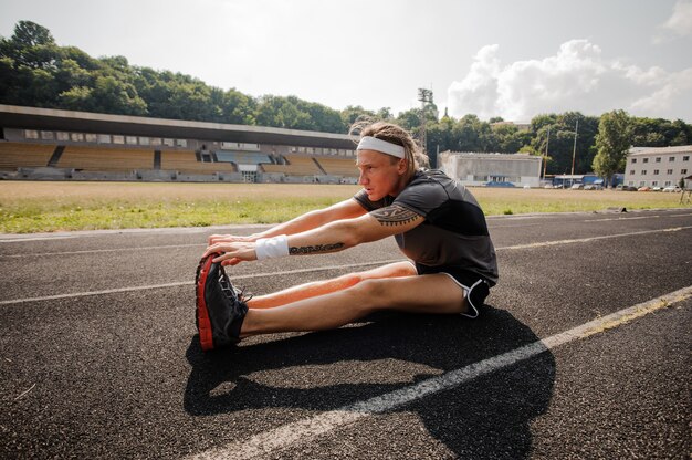 若い選手はランニングトラックでストレッチを行います