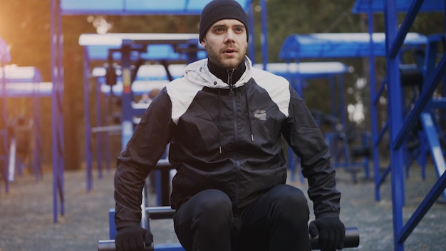 Young athlete man doing exercise at outdoor gym in winter park