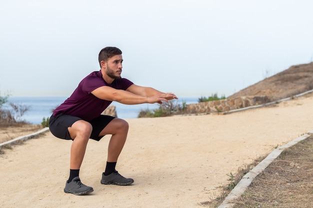 Young athlete man doing squats outdoor