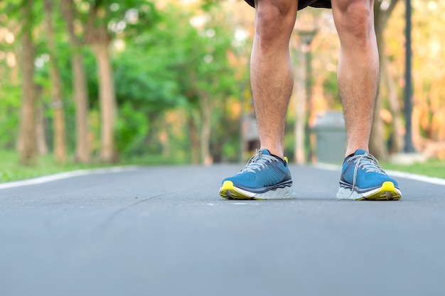 屋外の公園でランニングシューズを持つ若い選手男