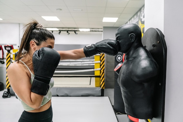 Young athlete punching to a dummy in gym