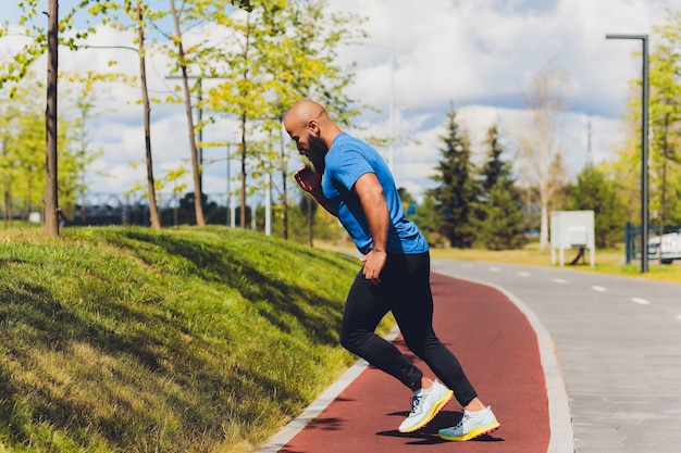 Young athlete running fast outdoors. Wearing sport cloth, doing wide step, demonstrating healthy way of life, wide shot.