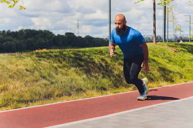 Young athlete running fast outdoors. Wearing sport cloth, doing wide step, demonstrating healthy way of life, wide shot.