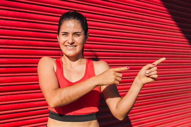 Young athlete in sportswear pointing her index fingers to the side