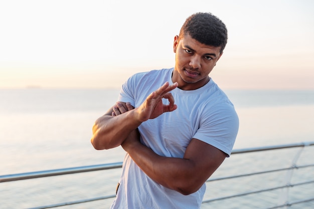 Young athlete standing and showing ok sign on pier