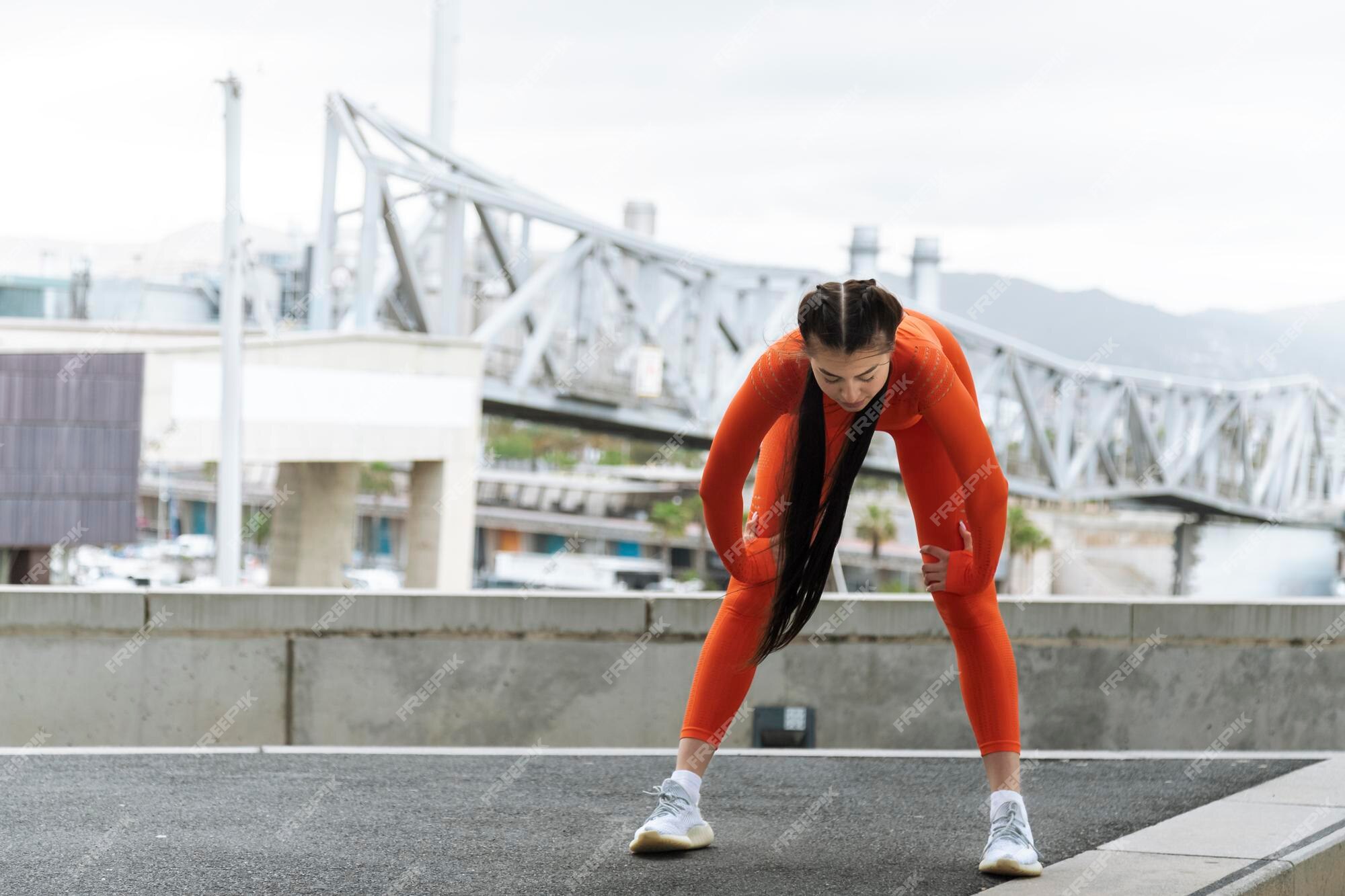 Premium Photo | Young athlete stop to rest while running. tired woman  bending over to catch her breath jogging in modern city. fitness concept.  active lifestyle. copy space.
