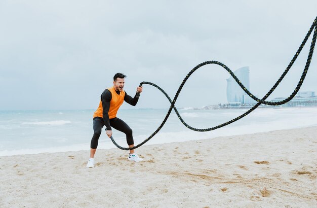 Young athlete training in the morning on the beach with ropes