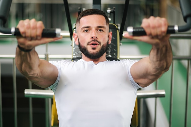 A young athlete trains in the gym Bodybuilder trains the muscules of the chest