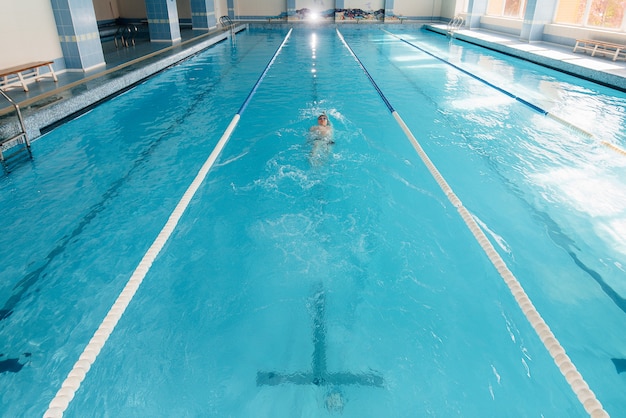 A young athlete trains and prepares for swimming competitions in the pool. Healthy lifestyle.