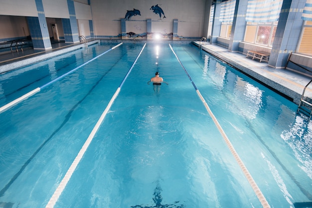 Foto un giovane atleta si allena e si prepara per le gare di nuoto in piscina. uno stile di vita sano.