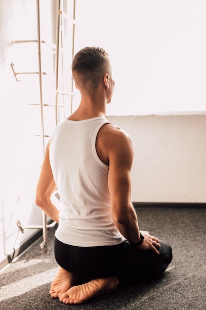 A young athlete in a white Tshirt sits near the window