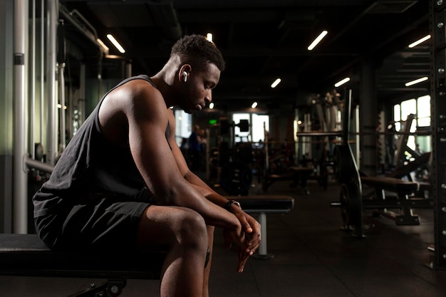 young athletic african american man sits in dark gym and thinks pensive athletic guy rests