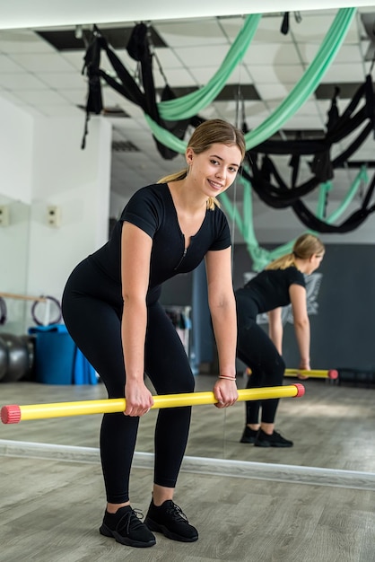 Young athletic attractive woman doing exercises with pilates stick