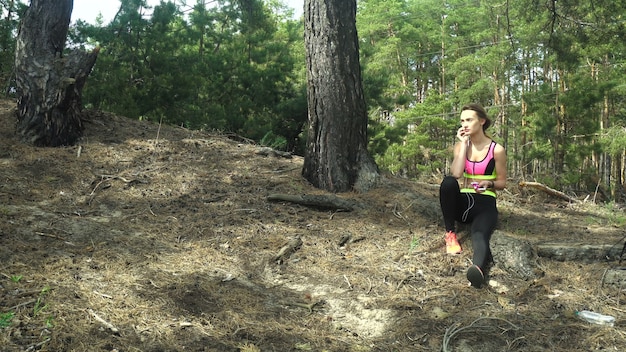 Молодая спортивная девушка слушает музыку и убегает в лесу