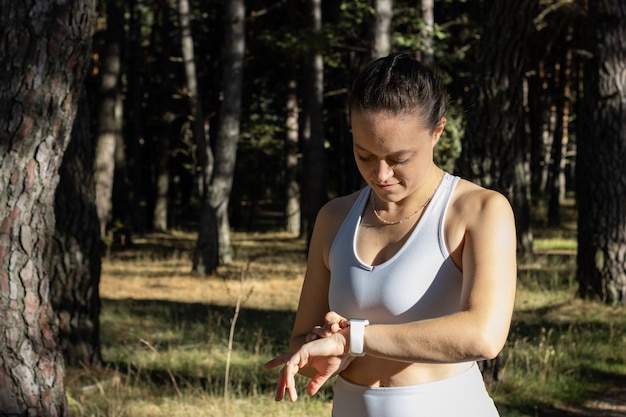 彼女のトレーニングセッションのストップウォッチタイマーを見ている若い運動少女