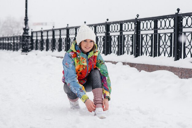 A young athletic girl ties her shoes on a frosty and snowy day. Fitness, running.