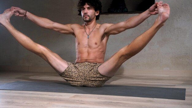 Un uomo giovane e atletico fa yoga e esegue asana