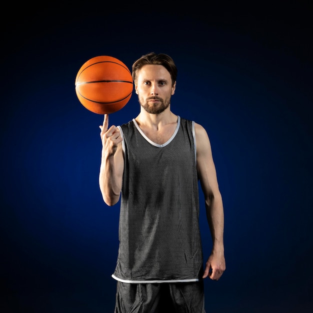 Foto giovane uomo atletico che tiene un pallone da basket