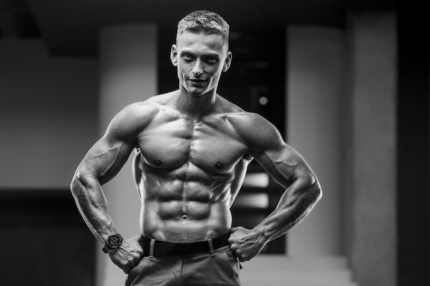 Фото Молодой спортивный человек накачивает мышцы в тренажерном зале на тренировке концепция спорта и здравоохранения