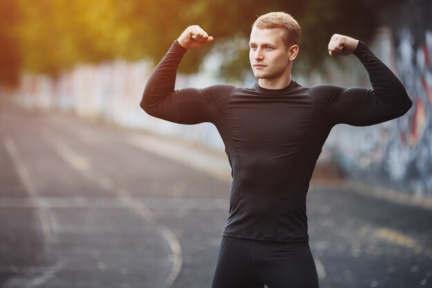 シェーカーを手にしたスタジアムの若いアスリート男夕方のジョギングの男