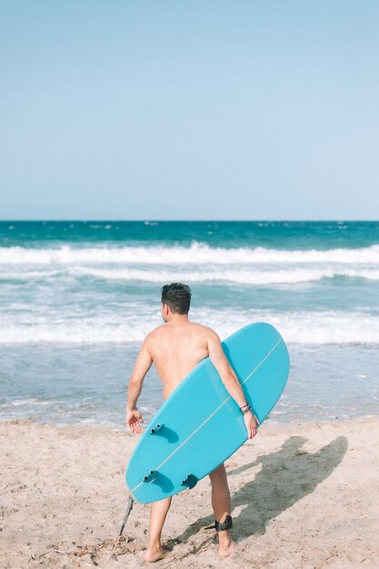 Young athletic man surfing on the beach