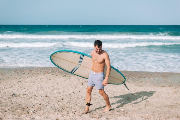 Young athletic man surfing on the beach