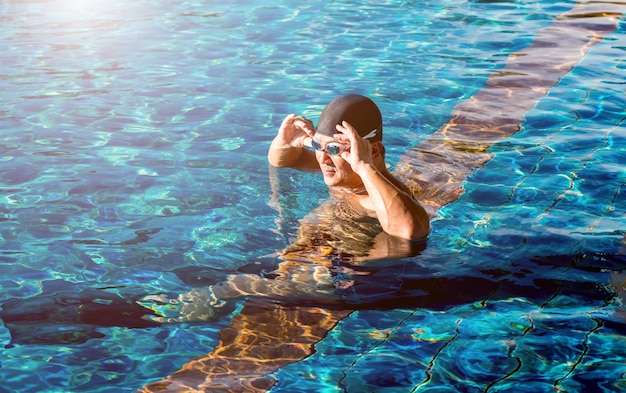 スイミングプールで泳いでいる若い運動男