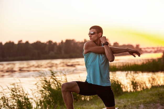 Young athletic man training at the riverside outdoors